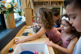 Children clean up a kitchen playset at the UM Dearborn Early Childhood Education