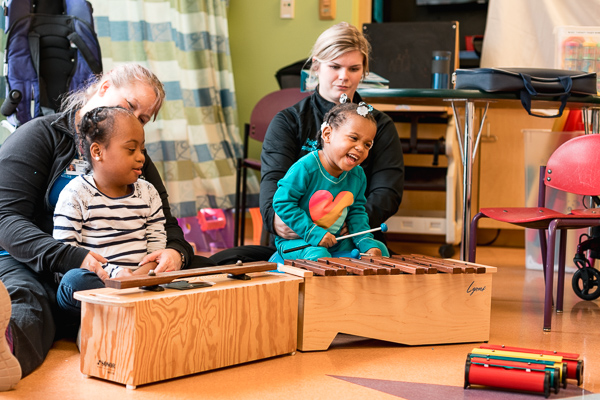 Patients Mackenzie Thomas and Darrenique Trotter play music during a therapy session