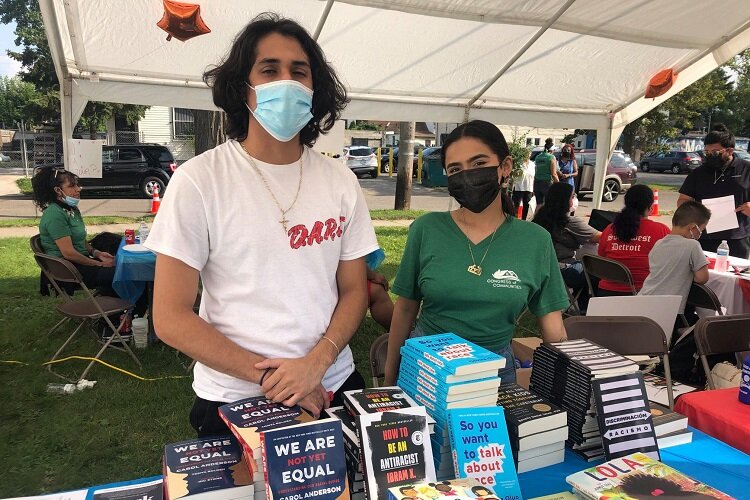 Young People with CoC stand at a booth with social jutice-themed books.