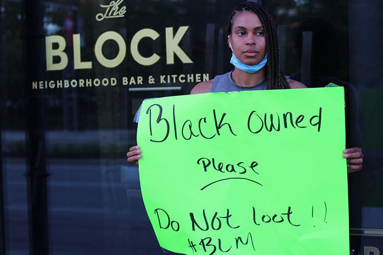 Stephanie Byrd holds up a sign that was posted on The Block.