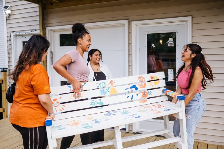 Members of the Detroit Creative Society carry a bench they designed.