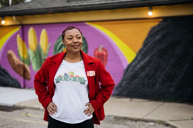 Teleah Mitchum stands by a mural at the E. Warren Farmers Market.