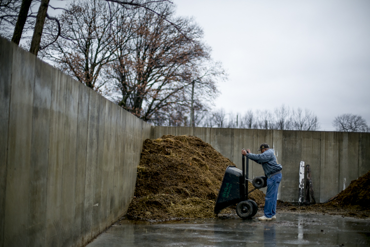  James Mills empties out a wheel barrel of manure.