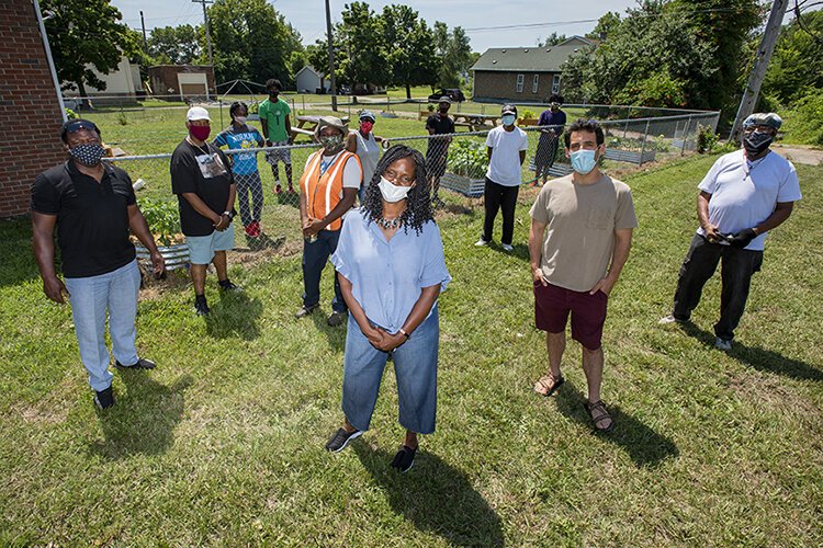 atrina Watkins, President of the Bailey Park Neighborhood Development Cooperation, center, poses with members of her team as well as neighborhood kids on Elmwood Street in Detroit. Bailey Park is one of this year's recipients.