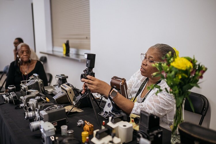 A participant in the photovoice exhibit shows off her vintage camera collection.