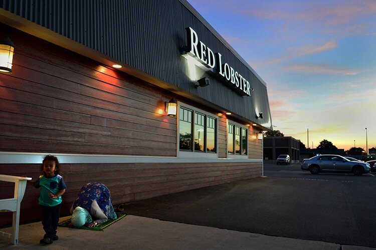 Community activist Hazel Gomez prays in front of Red Lobster, a representation of how Muslims practice their faith in America.