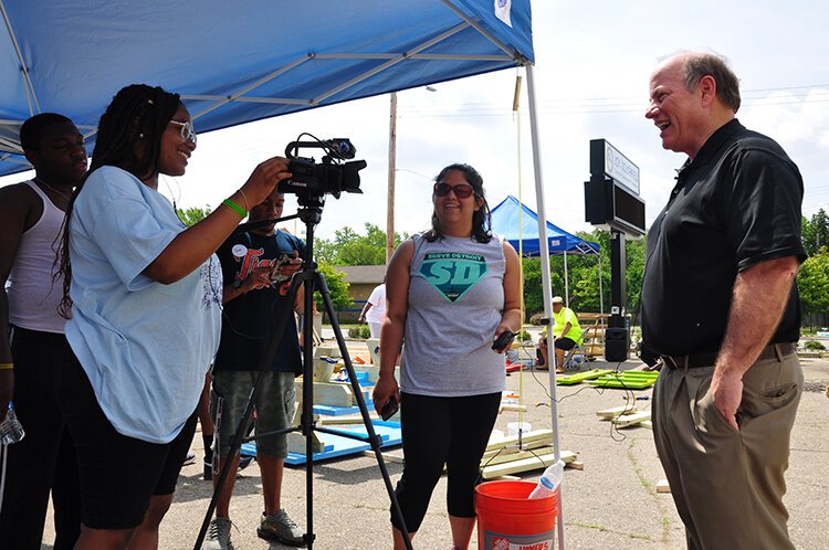 Rodney Bridges, Taylin Hodges, and Mona Ali interview Mayor Mike Duggan at a community picnic table building event.