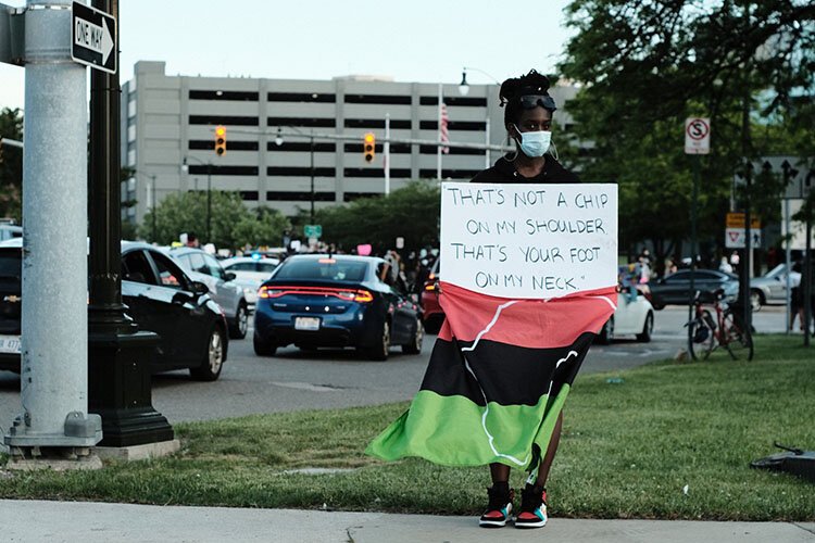 A protester holds up a sign Friday in Detroit.