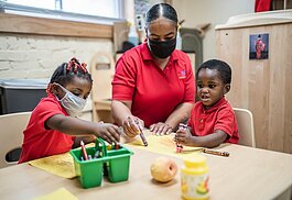 Early Education teacher Carla Wasson colors with students at Village of Shiny Stars