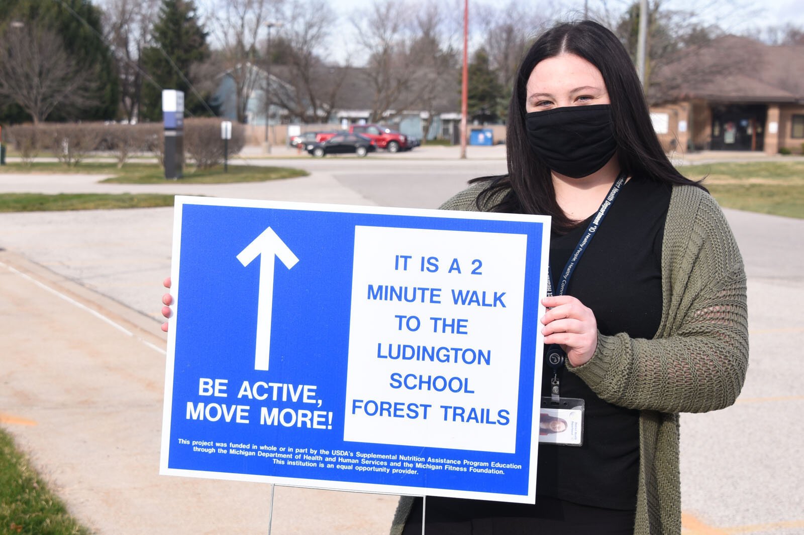 Erin Barrett holds a walking trail sign in Ludington.