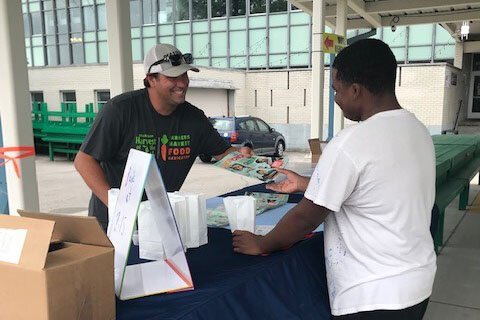 Farmers Market Food Navigator Josh Miller talks to a young visitor.