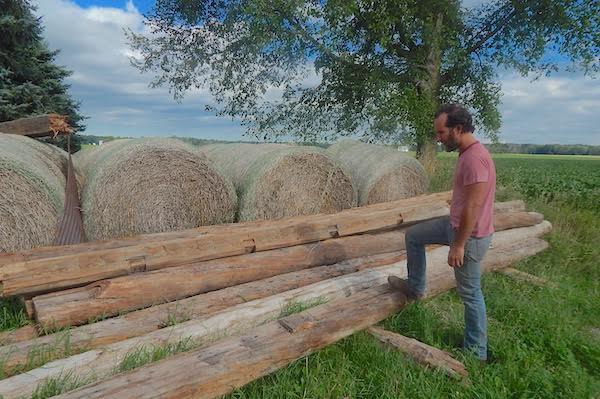 Hocking next to wood from a barn that he will add to his boat installation