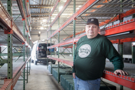 Jeff Adams stands between the growing racks at Artesian Farms