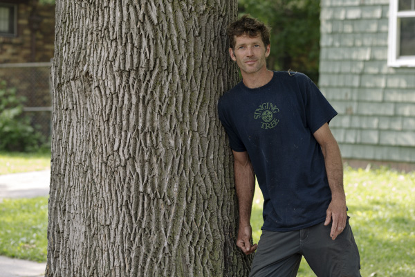 Kevin Bingham stands next to a healthy ash tree in front of his home