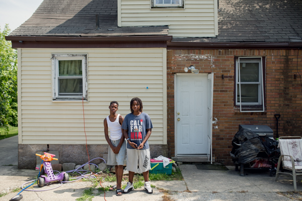 Ky'Shaun Gibson, left, with his step brother Davion Robertson, right, standing in front of the backside of Shakiya's saved home