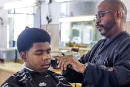 ​Lucas, 13, getting his hair cut by Metro Detroit Barber College owner Raymond Ware