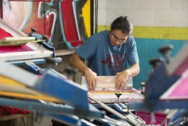 A member of Stitching Up Detroit inks a shirt at the screen printing facility at Grace in Action