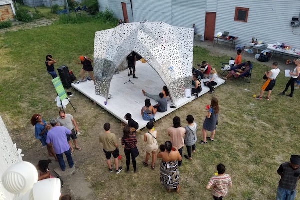 The Oakland Avenue Artist Coalition and the Detroit Poetry Society Poetry celebrate pizza night at the American Riad under and around its canopy