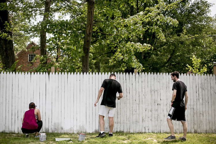 Volunteers from Elite Detroit paint a fence