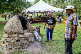 Mama Hanifa, education and outreach director of the Detroit Black Community Food Security Network, explaining the earth oven to a guest