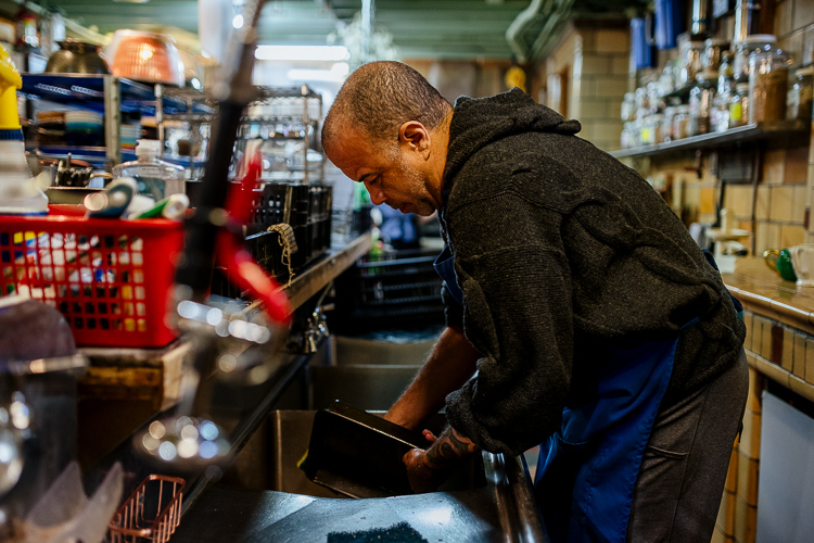 Micheal Piper doing dishes in the cafe. Piper is a member who volunteers once a week.