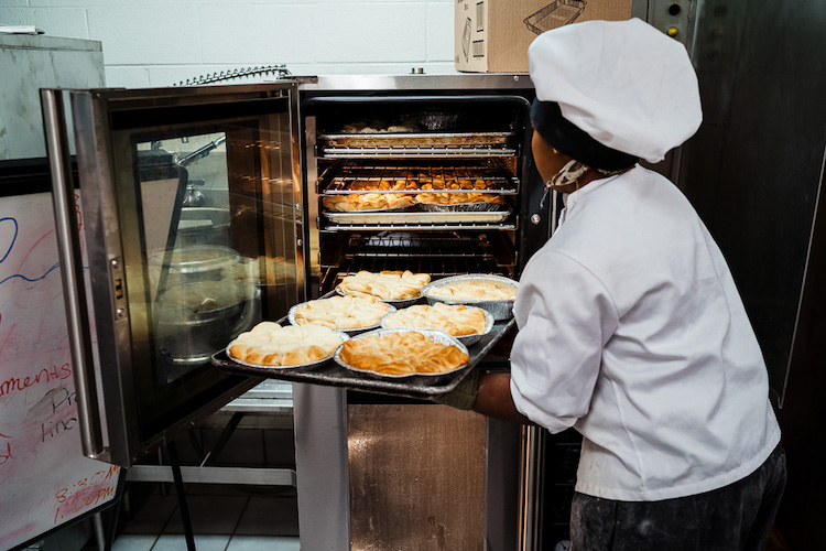 Student puts pies in the oven at Golightly's Bakeshop