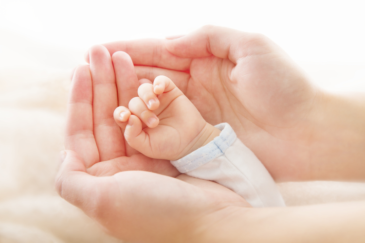 A mother holds her baby's hand.